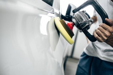 Araba tamiri, oto tamirhanesinde orbital parlatıcıyla el işi. Seçici odak.