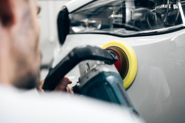 Araba tamiri, oto tamirhanesinde orbital parlatıcıyla el işi. Seçici odak.