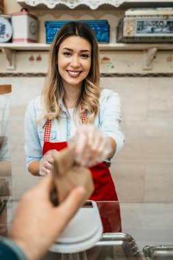 Tatlı bir yemek evinde ya da fırında çalışan genç ve güzel bir bayan satıcı. Lezzetli tatlılar satıyor ve paketliyor..