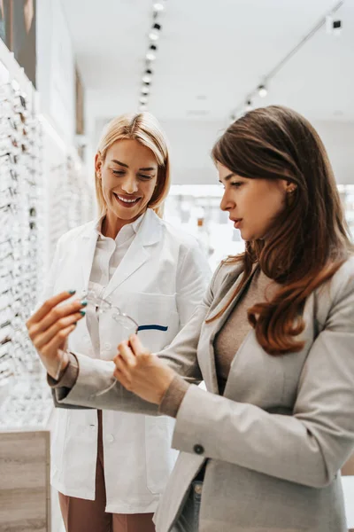 Schöne Und Modische Frau Wählt Brillengestell Modernen Optikgeschäft Verkäuferin Hilft — Stockfoto