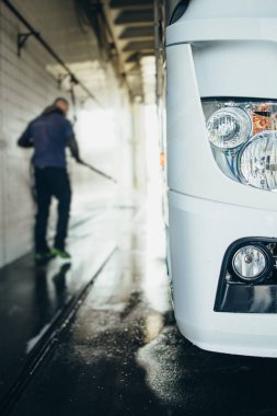 Şapkalı ve güneş gözlüklü profesyonel kamyon şoförü büyük ve modern bir kamyonun önünde duruyor. Parlak güneşli bir gün. İnsanlar ve ulaşım kavramı.