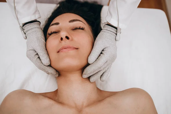 Micro sensory electrical BIO EMS micro-current treatment for face and body electrode stimulation with conductive gloves. Anti wrinkle and anti-aging lifting. Selective focus.