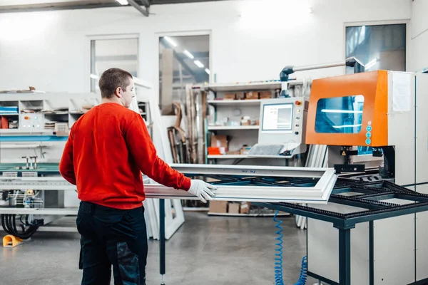 Young male worker assembling products in modern PVC and aluminum doors and windows production factory.