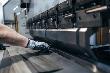 Hidrolik metal bükme makinesi üzerinde çalışan koruyucu eldivenli işçilerin yakın çekim görüntüleri. Endüstriyel kavram.