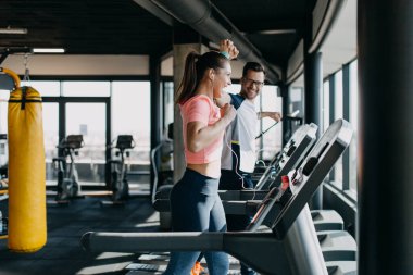Modern spor salonunda koşu bandında koşan genç erkek ve kadın..