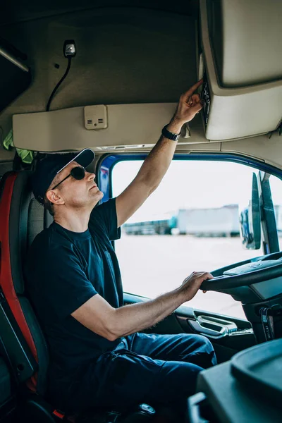 Experienced truck driver sitting in his truck and waiting for a new driving route.