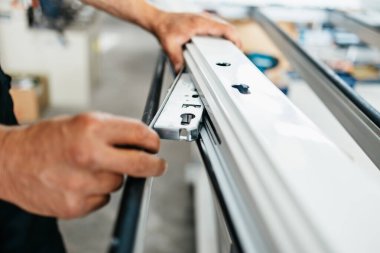 Genç erkek işçi modern PVC ve alüminyum kapı ve pencere üretim fabrikalarında ürünleri birleştiriyor. İşçi ellerinin aşırı yakın çekimi..