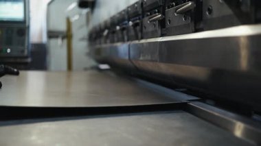 Bir fabrikada hidrolik baskı fren makinesi kullanan bir metal işçisinin yakından görüntüsü endüstriyel üretim ve üretim işlemleri için hassas büyük bir çelik levhayı büküyor.