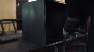 Koruyucu maske ve eldiven takan endüstriyel işçiler bir atölyede metal bir yapıyı kaynak yaparak yüksek sıcaklıktaki yay sürecinden parlak ışıklar ve kıvılcımlar yaratıyor.