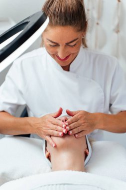 Güzel, rahat, genç bir kadın gözleri kapalı uzanmış güzellik merkezinde ya da kuaförde yüz masajı yapıyor. Bayan müşteri cilt bakımı tedavisinden zevk alıyor. Sağlık ve güzellik kavramı.