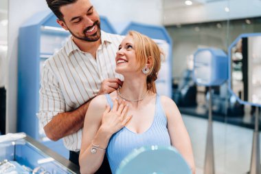 Mutlu genç çift kuyumcudan lüks mücevherler seçip almaktan zevk alıyor. Kadın mutlu ve heyecanlı..