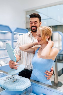 Mutlu genç çift kuyumcudan lüks mücevherler seçip almaktan zevk alıyor. Kadın mutlu ve heyecanlı..