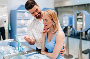 Mutlu genç çift kuyumcudan lüks mücevherler seçip almaktan zevk alıyor. Kadın mutlu ve heyecanlı..