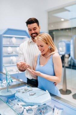 Mutlu genç çift kuyumcudan lüks mücevherler seçip almaktan zevk alıyor. Kadın mutlu ve heyecanlı..