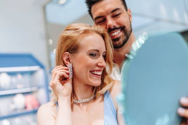 Mutlu genç çift kuyumcudan lüks mücevherler seçip almaktan zevk alıyor. Kadın mutlu ve heyecanlı..