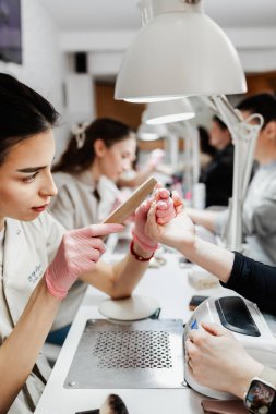 Modern bir güzellik salonunda çalışan profesyonel manikürcüler. Tatmin olmuş kadın müşteriler kaplıca merkezinde manikür tedavisi görüyor..