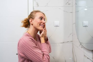 Bir kadın, modern bir mutfak lavabosunda akarsu altında tencere ve yemek takımı yıkıyor..