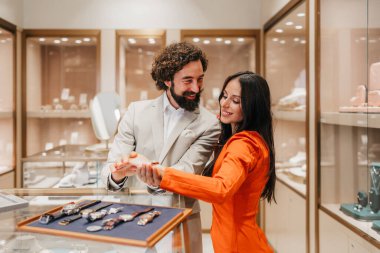 Profesyonel bir satıcı lüks bir mücevher dükkanında lüks bir saat denerken şık bir kadına yardım eder..