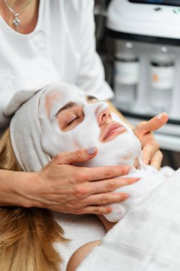 Profesyonel estetisyen, spa kliniğinde kadın bir müşteriye oksijen köpüğü kullanarak derin bir yüz tedavisi uyguluyor..