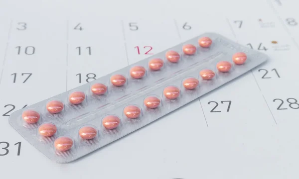 Close up birth-control pill with date of calendar background, health care and medicine concept