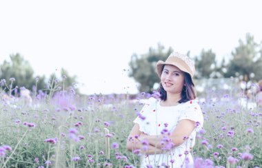 Asyalı mutlu kadın portresi çiçek bahçesiyle gülümsüyor, seçici odaklanma.