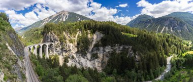 Rhaetian Demiryolu 'nun tarihi Landwasserviadukt' u güneşli bir günde İsviçre Alpleri 'nde derin bir vadi boyunca mühendislik harikaları ve nefes kesici manzaralar sergiliyor..