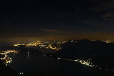 Niederbauen Kulm 'dan Lucerne Gölü' nün sakin sularının kenarına kurulmuş aydınlık şehir Lucerne 'e bakan nefes kesici bir panoramik manzara. Binalar karanlık gökyüzüne karşı hafifçe parıldıyor, gökyüzünde yıldızlar görünüyor, sihirli bir...