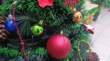 Noel ağacı, kırmızı, mavi, parlak, yeşil ve kırmızı boncuklu çam iğnelerinin arasına yerleştirilmiş altın süsler sergiliyor..