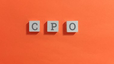 Turuncu arka planda tahta bloklar üzerine CPO harfleri, Baş Ürün Sorumlusu ve Ürün Yöneticisini sembolize ediyor