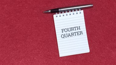 Dördüncü çeyreğin hatırlatıcısını gösteren not, önemli yıl sonu finansal planlama ve teslim tarihlerini sembolize eden zengin kırmızı desenli materyalin üzerinde metalik bir kalemin yanında duruyor..