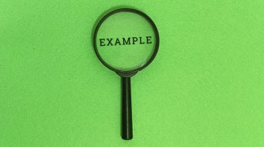 Büyüteç, yakın denetim ve görsel analizin temel kavramlarını temsil eden canlı yeşil keçeli arka plan üzerindeki yazdırılmış sözcük örneğini genişletir..