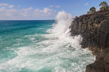 Dev bir dalga, Avustralya 'nın Yeni Güney Galler bölgesindeki Fingal Tepeleri' nde altıgen yapılandırılmış volkanik kayalar ve kayalıkların dibinde bir kazan ile bazalt kayalıklara çarpar..