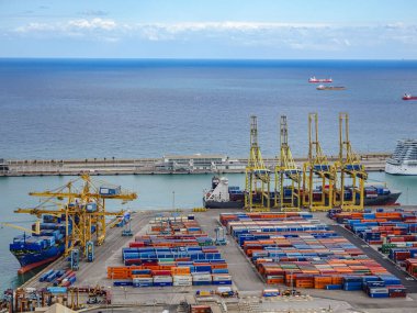 Barselona, İspanya. 5 Ekim 2025. Hareketli limandaki renkli nakliye konteynırları ve kargo vinçlerinin hava manzarası sakin mavi deniz ve arka planda tankerler.