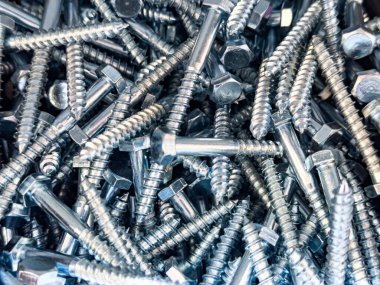 Rastgele etrafa saçılmış parlak uğursuz kafa vidaları. Metalik doku arka planı inşaat, onarım ve endüstriyel kavramlar için idealdir.