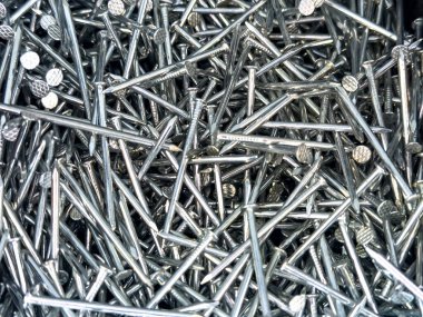 Kafaları rastgele dağılmış parlak çelik çivilerin üst görüntüsü. Donanım, inşaat, DIY veya endüstriyel altyapı için mükemmel.