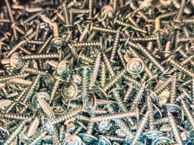 Yığınla çamaşır makinesiyle parlak vidaları yakın çekim. Sıcak metalik tonlara sahip endüstriyel bir arka plan. İnşaat, araç gereç veya mekanik doku temaları için mükemmel.