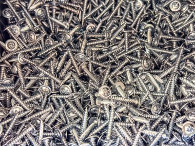 Makro fotoğraf, çamaşır makinesiyle kendini beceren gümüş vidalar, bir yığın içinde sıkıca paketlenmiş. Endüstriyel donanım arkaplanı, inşaat veya DIY temaları için uygun.