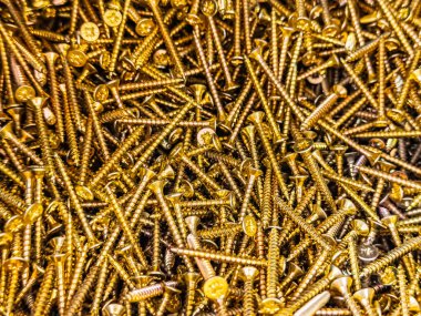 Parlak altın vidaların yakın plan görüntüsü yoğun dokulu bir arka plan oluşturuyor. Endüstriyel, DIY ve inşaat temaları için ideal.