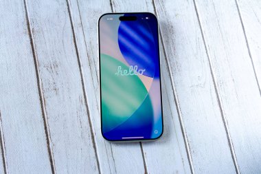 Yılan pençesi. Polonya. 7 Kasım 2025. Renkli bir merhaba ekranı olan modern akıllı telefon beyaz ahşap arka plana yerleştirilmiş. Üst görünüm