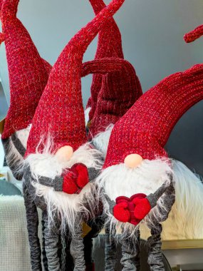 Uzun kırmızı şapkalı, beyaz sakallı ve kırmızı eldivenli şirin Noel cücesi süslemeleri sergilenmekte..