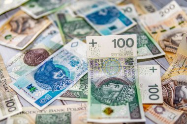Polonya zloti banknotları bir yüzeye saçılmış, renkli para birimi değerlerini finansal veya para geçmişi olarak göstermektedir.
