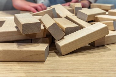 Ahşap bloklar arka planda oynayan bir çocukla bir masanın üzerine saçılmış. Doğal oyuncaklara ve yaratıcı oyunlara yakından bak.