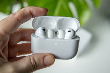 Yılan pençesi. Polonya. 3 Aralık 2025. El ele tutuşan Airpod Pro 3 şarj çantasının içinde kulaklıklar ve temiz bir arkaplan.