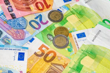 Renkli para birimi tasarımı, güvenlik detayları ve finansal temalı kompozisyonda karışık mezhepleri gösteren çeşitli avro banknotları ve sikkeler birlikte düzenlendi.