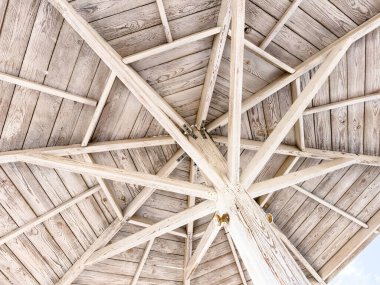 Aşağıdan görünen kirişli ahşap çatı yapısı geometrik desen oluşturuyor. Doğal ahşap dokusu soyut bir mimari arkaplan yaratır..