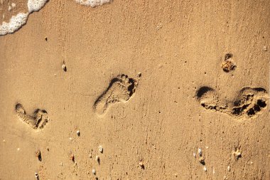 Denize yakın ıslak kumda ayak izleri. Yolculuk kavramı, farkındalık, yalnızlık, hatıralar, geçen zaman ve doğada insan varlığı..
