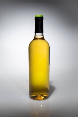 Hafif arka planda, yumuşak bir yansımayla izole edilmiş bir şişe beyaz şarap. Reklam, markalaşma, ambalaj tasarımı, restoran ve içecek kavramları için uygun minimal stüdyo ürünü.