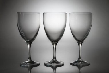 Arka planda izole edilmiş üç boş şarap kadehi. Restoran, bar, şarap tatma, kutlama, menü tasarımı ve zarif masa dekorları için minimalist cam eşyalar..