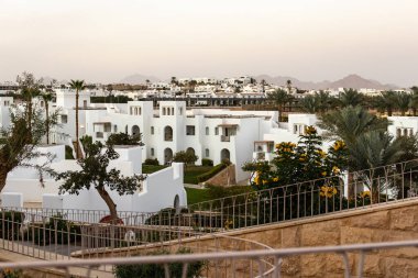 Palmiye ağaçları ve bahçelerle çevrili beyaz tatil köyleri. Modern mimari, lüks seyahat merkezi, tatil ve konukseverlik kavramına sahip Akdeniz Oteli kompleksi.