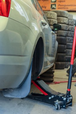 Lastik değiştirme sırasında oto tamir atölyesinde hidrolik zemin krikosu olan araba kaldırıldı. Otomotiv bakımı ve araç hizmeti kavramı.